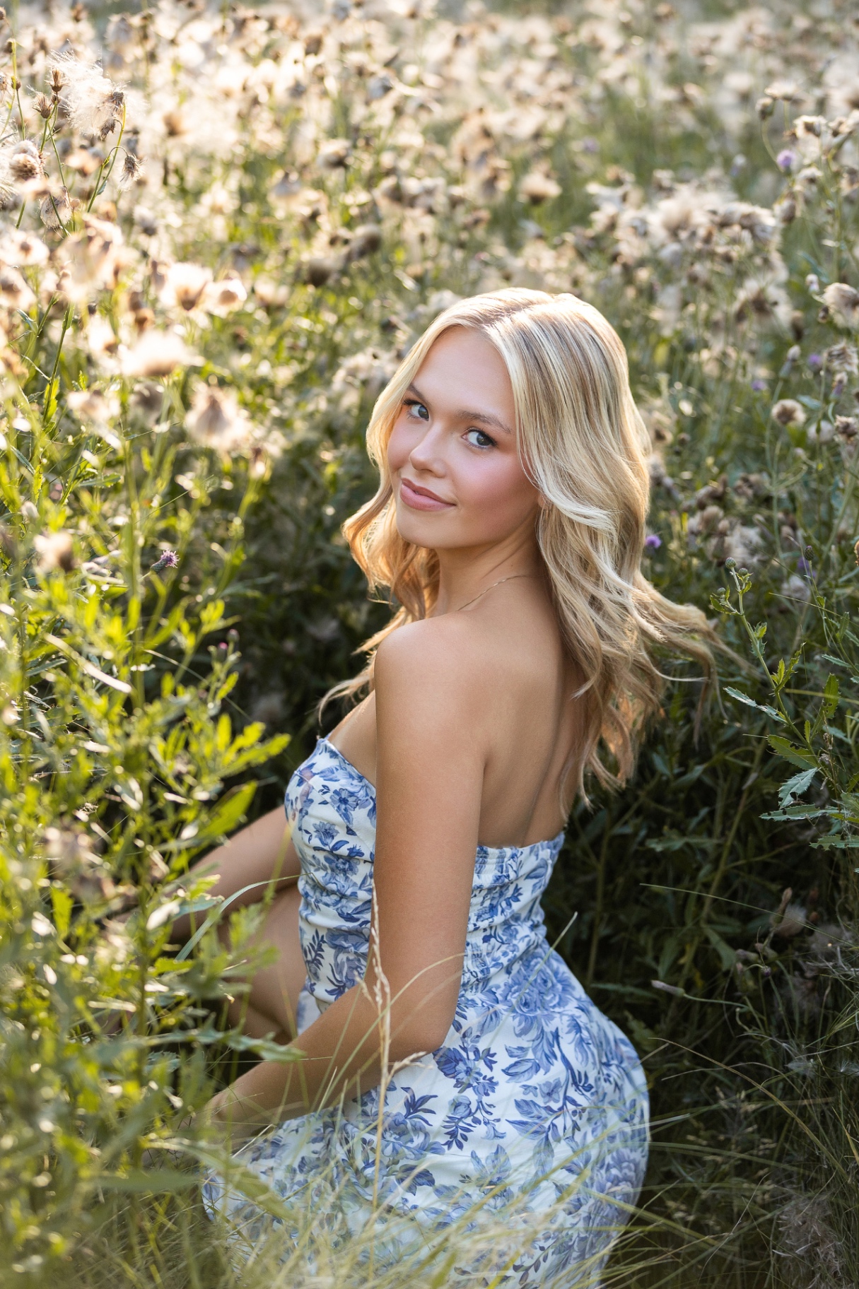 Ellis Jayne in a blue floral dress surrounded by sunlit wildflowers