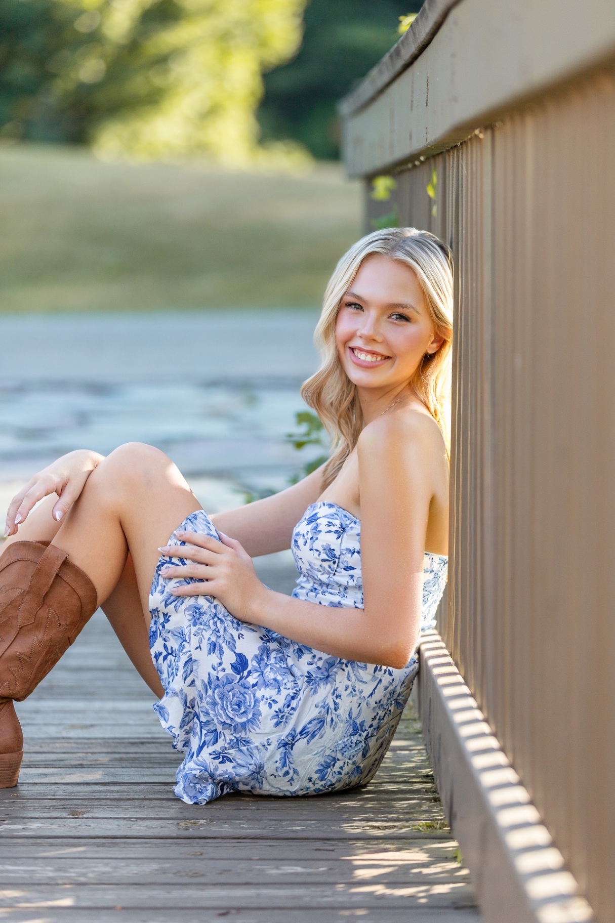 Ellis Jayne smiling while seated on a sunlit wooden dock