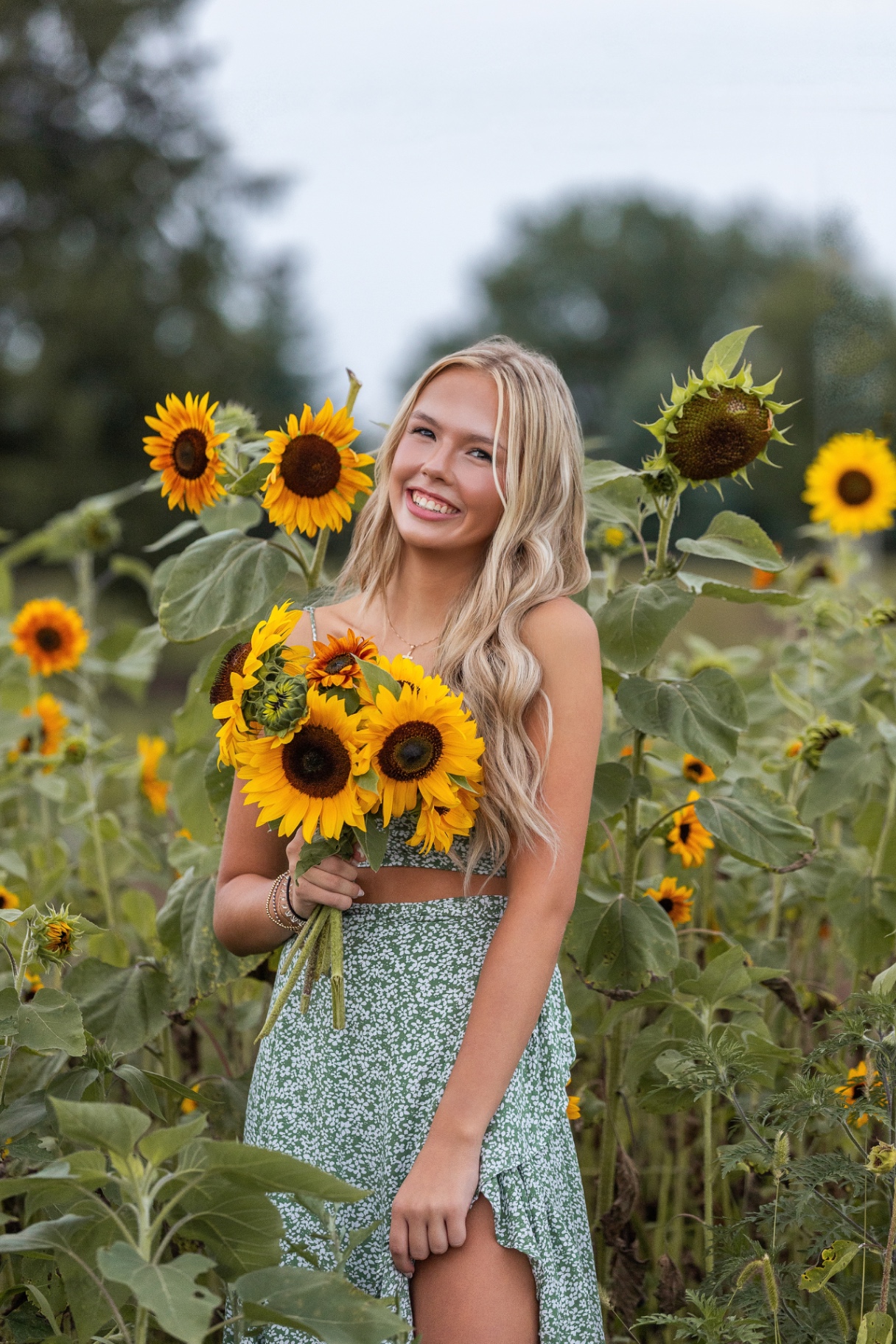 Ellis Jayne smiling in a sunflower field wearing a green floral set